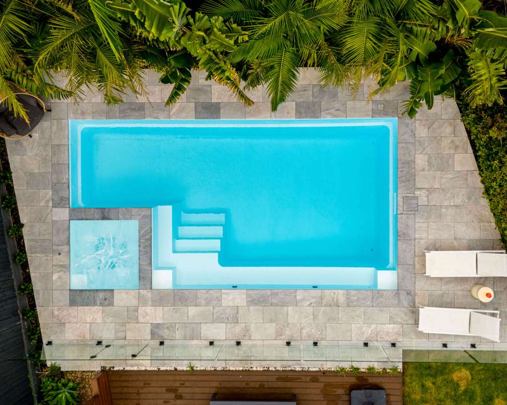 Aerial view of a modern backyard swimming pool with clean landscaping, photographed by Forma Media.